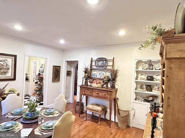 dining space featuring ornamental molding and light hardwood / wood-style flooring