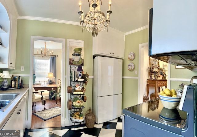 kitchen featuring a notable chandelier, ornamental molding, white fridge, and white cabinets