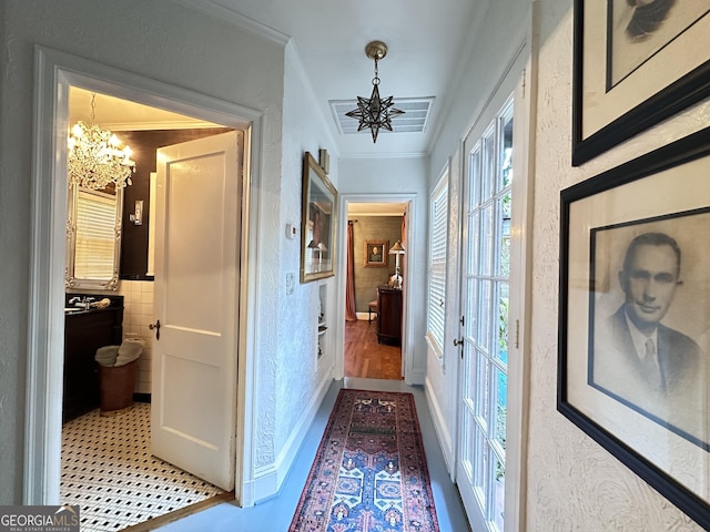 corridor featuring crown molding, tile walls, and an inviting chandelier