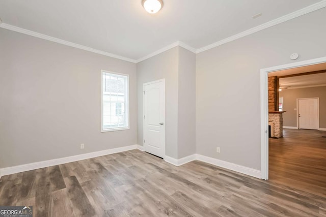 unfurnished room featuring hardwood / wood-style floors, crown molding, and a brick fireplace