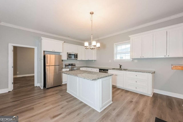 kitchen with light stone countertops, stainless steel appliances, sink, pendant lighting, and white cabinetry