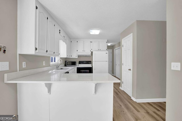 kitchen with electric range, stainless steel microwave, freestanding refrigerator, a peninsula, and light countertops