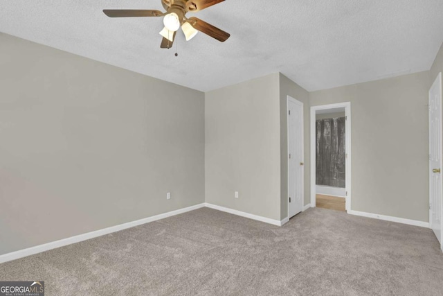 spare room featuring a textured ceiling, ceiling fan, and light carpet