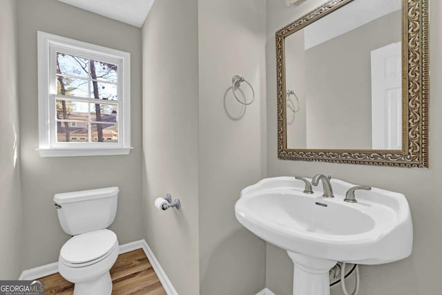 half bathroom with a sink, wood finished floors, toilet, and baseboards