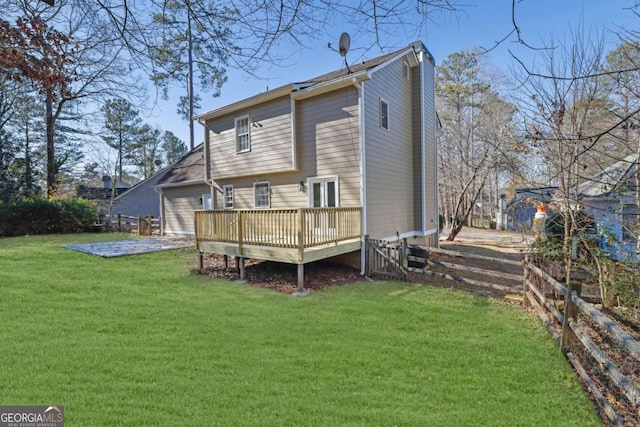 rear view of house with fence, a deck, and a lawn