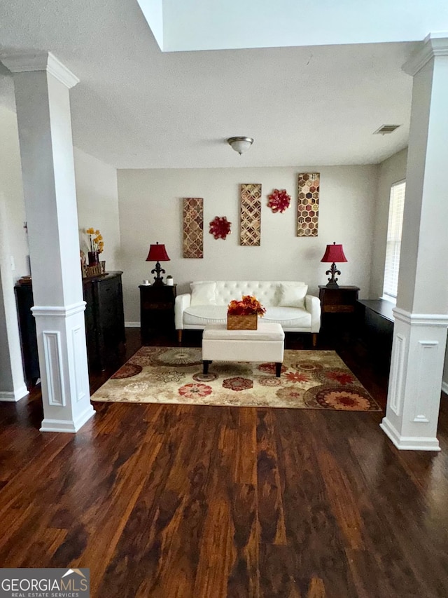 living room featuring dark wood-type flooring and ornate columns