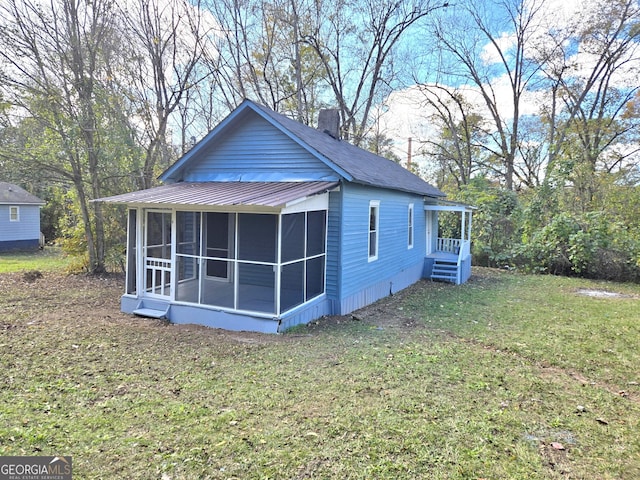 view of home's exterior with a sunroom and a lawn