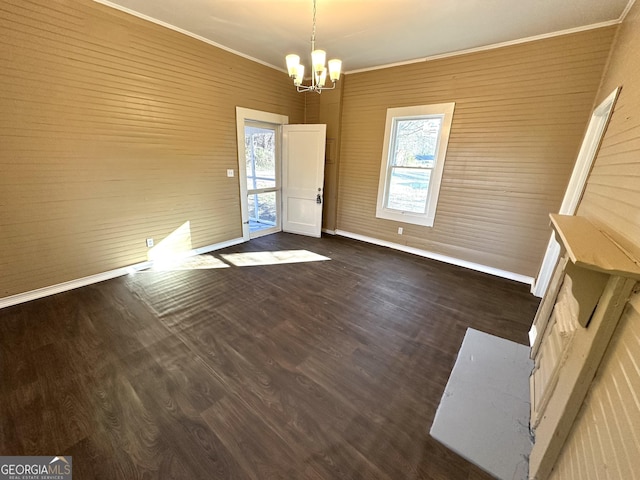 unfurnished dining area with plenty of natural light, dark hardwood / wood-style flooring, crown molding, and a chandelier