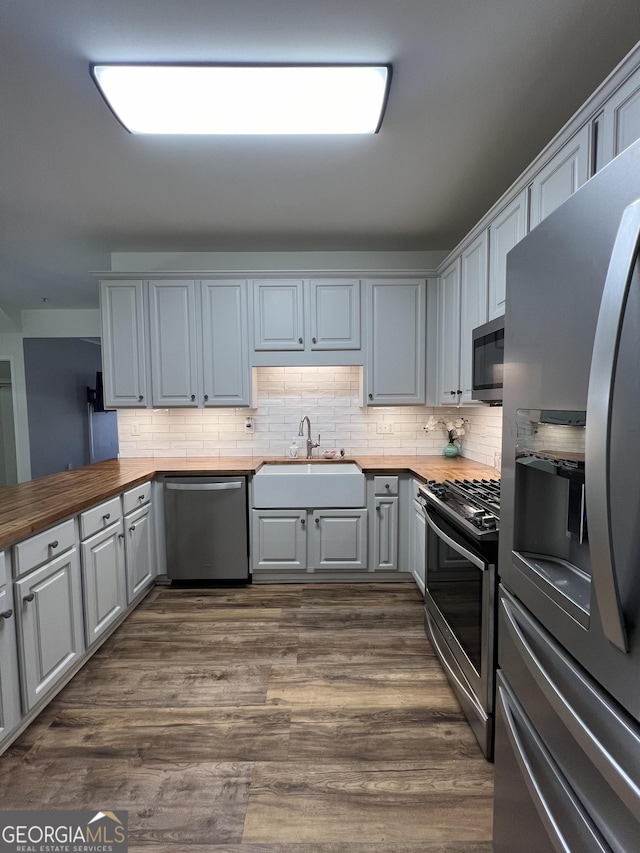 kitchen featuring butcher block counters, stainless steel appliances, gray cabinetry, dark hardwood / wood-style floors, and sink