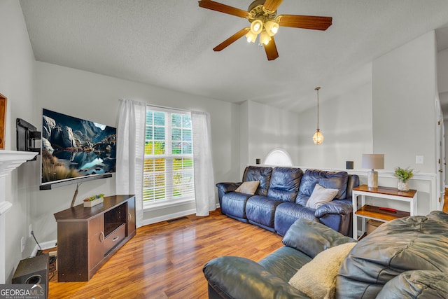 living room with ceiling fan, hardwood / wood-style floors, and a textured ceiling