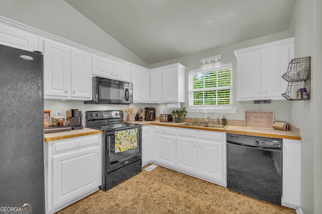 kitchen featuring white cabinetry, sink, black appliances, and vaulted ceiling