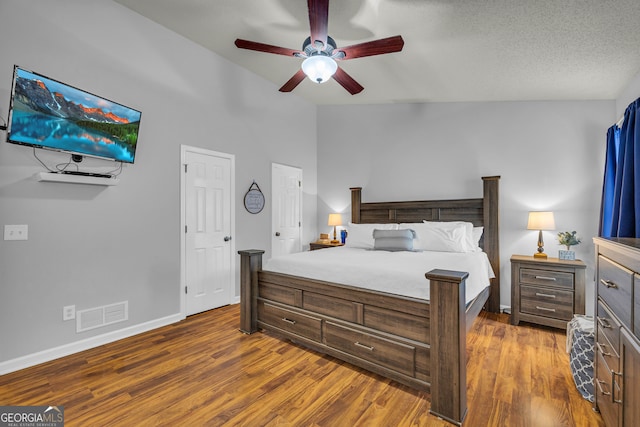 bedroom featuring ceiling fan, dark hardwood / wood-style flooring, a textured ceiling, and vaulted ceiling