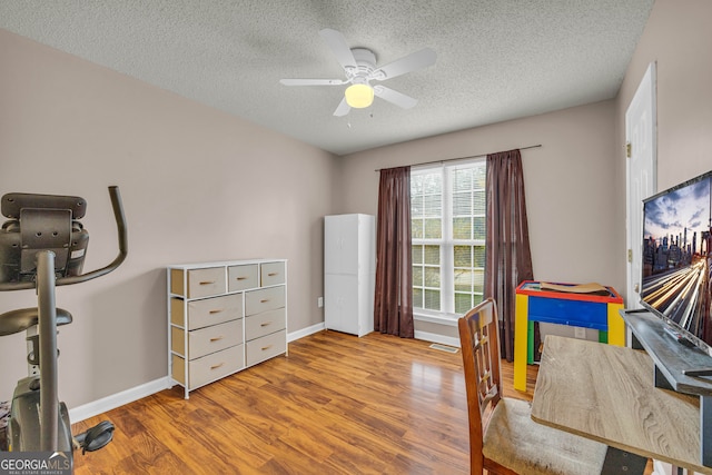 home office featuring ceiling fan, hardwood / wood-style floors, and a textured ceiling