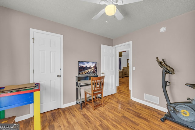 home office featuring ceiling fan, wood-type flooring, and a textured ceiling