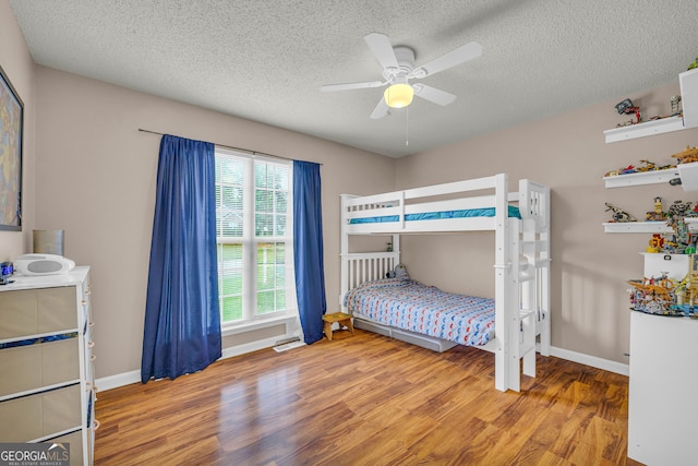 bedroom with a textured ceiling, light wood-type flooring, and ceiling fan