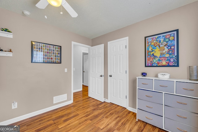 bedroom featuring a textured ceiling, light hardwood / wood-style flooring, and ceiling fan