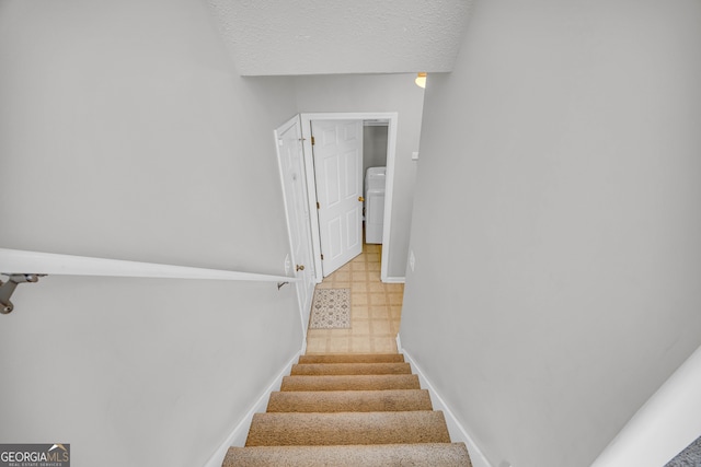 stairway featuring a textured ceiling and washer / clothes dryer