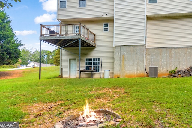 back of house with a yard, an outdoor fire pit, a wooden deck, and central air condition unit