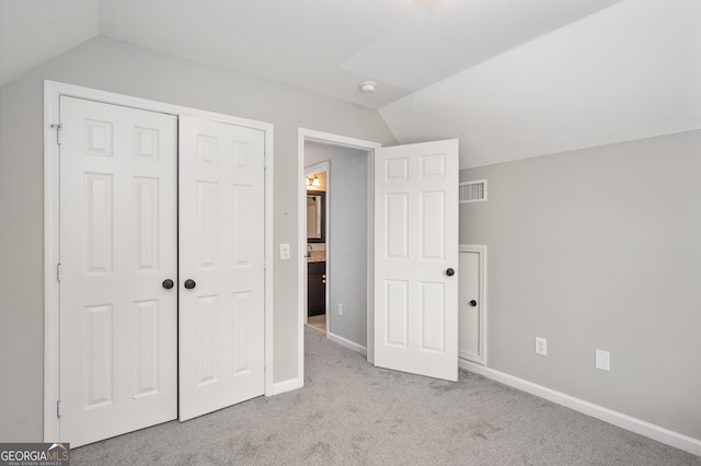 unfurnished bedroom with lofted ceiling, light colored carpet, and a closet