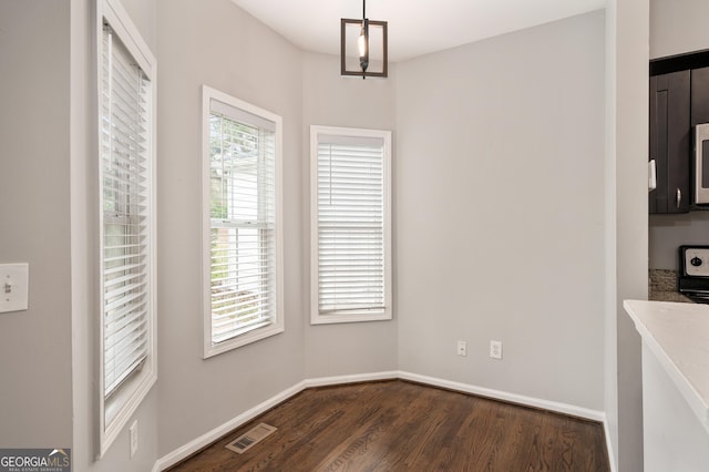 unfurnished dining area with dark wood-type flooring