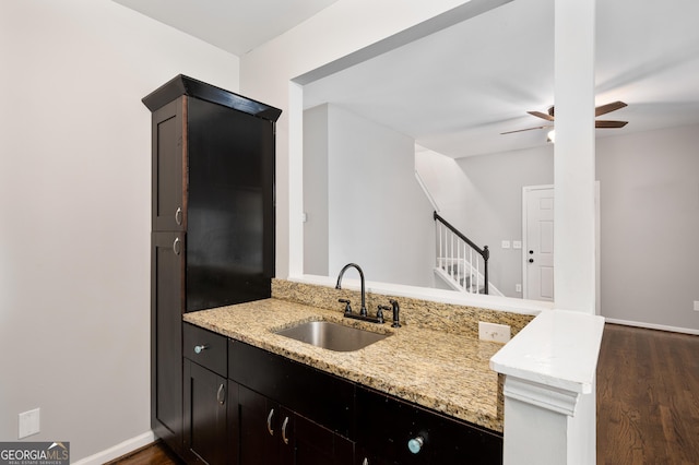 kitchen with dark hardwood / wood-style floors, sink, ceiling fan, kitchen peninsula, and light stone countertops