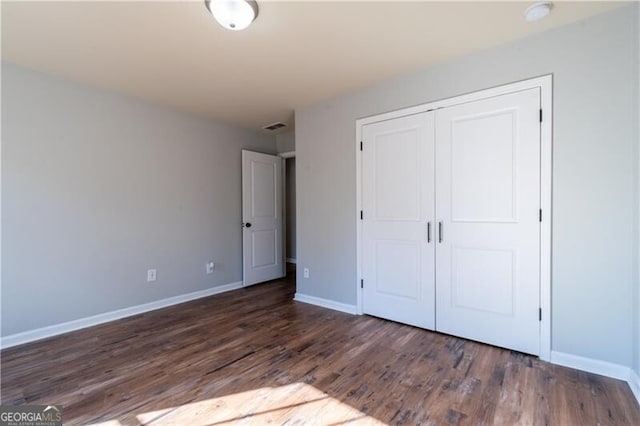 unfurnished bedroom with a closet and dark wood-type flooring