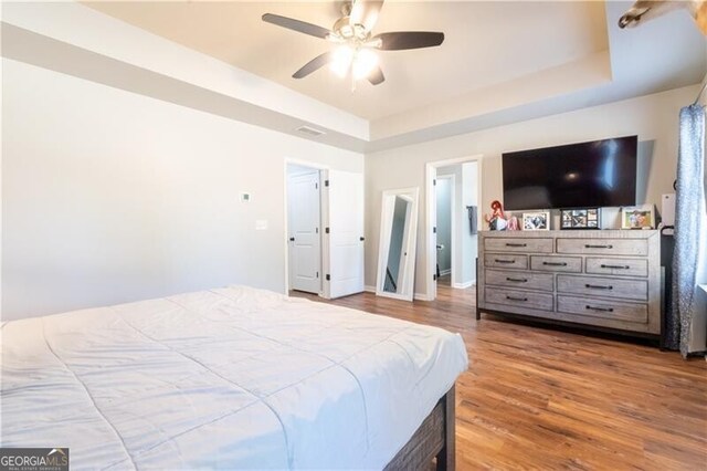 bedroom featuring a tray ceiling, ceiling fan, and hardwood / wood-style flooring