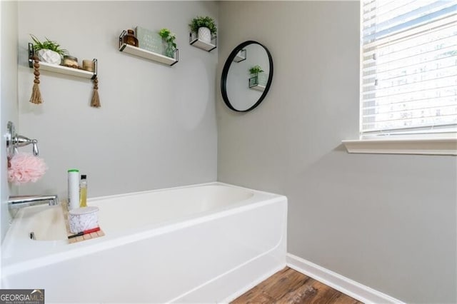 bathroom featuring wood-type flooring and a tub