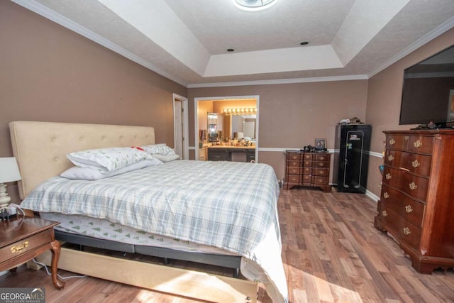 bedroom featuring a raised ceiling, wood-type flooring, and ornamental molding