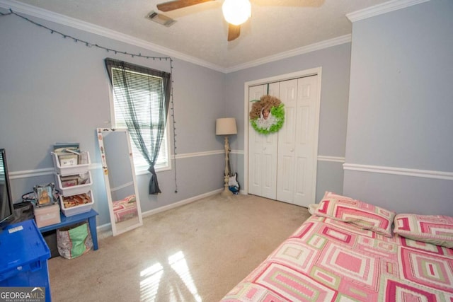 bedroom with crown molding, ceiling fan, a closet, and light colored carpet