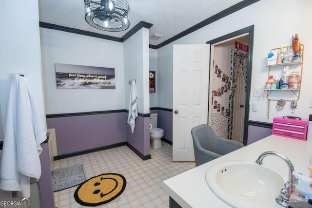 bathroom featuring vanity, a textured ceiling, toilet, and ornamental molding