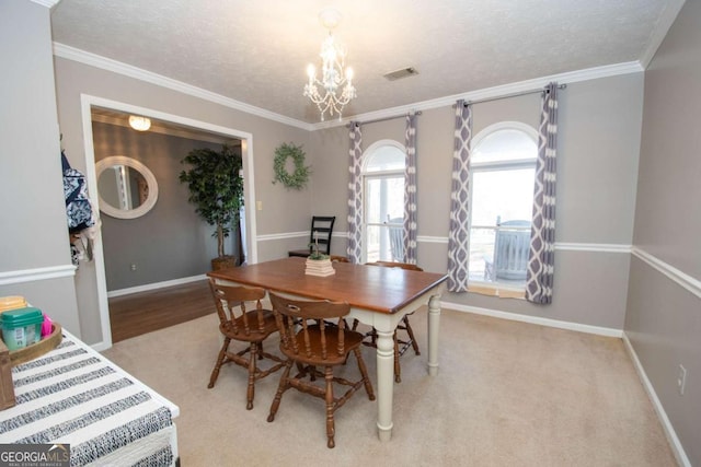 dining room featuring light colored carpet, ornamental molding, a textured ceiling, and a chandelier