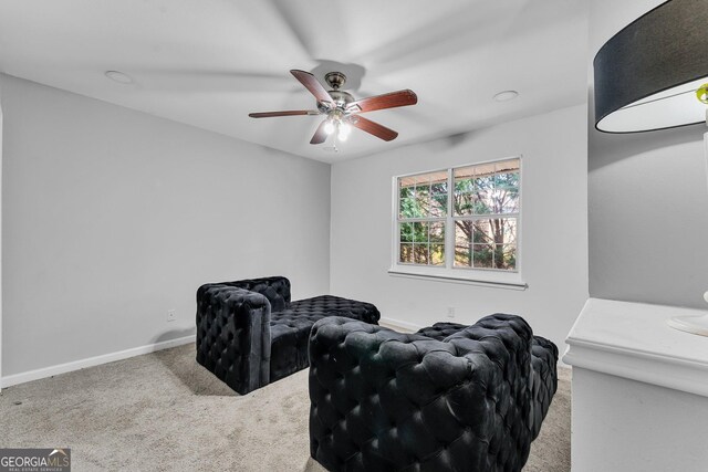 living area with ceiling fan and carpet