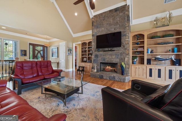 living room featuring wood-type flooring, high vaulted ceiling, ceiling fan, and a stone fireplace