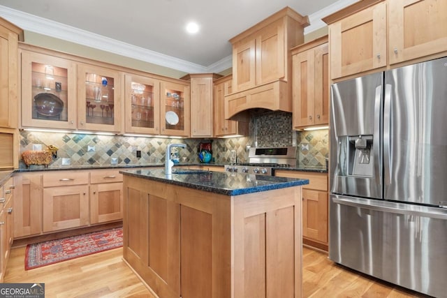 kitchen with a center island with sink, dark stone countertops, appliances with stainless steel finishes, tasteful backsplash, and custom range hood