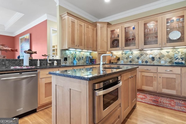 kitchen with sink, decorative backsplash, dark stone countertops, an island with sink, and stainless steel appliances