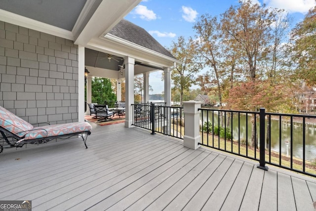 wooden deck with ceiling fan and a water view