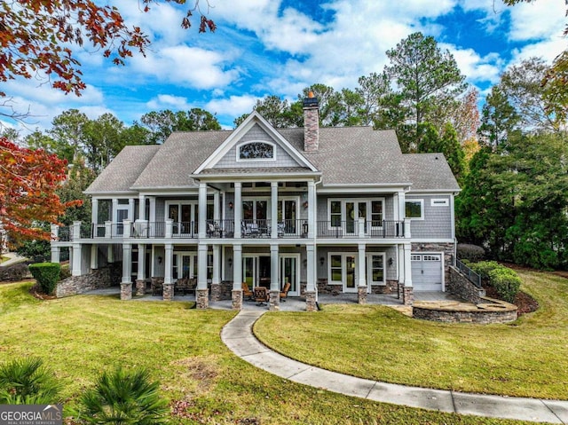 rear view of property featuring french doors, a balcony, a garage, and a patio area