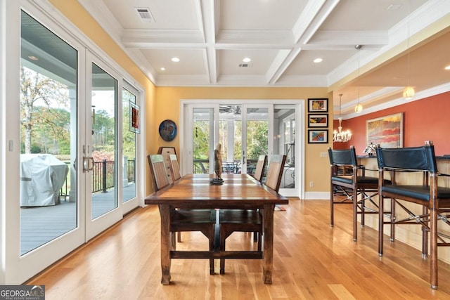 dining room featuring light wood-type flooring, ornamental molding, coffered ceiling, beam ceiling, and a chandelier