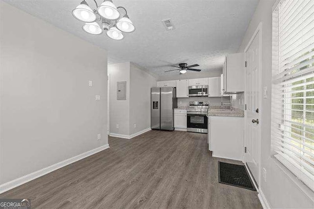 kitchen with appliances with stainless steel finishes, ceiling fan with notable chandelier, a textured ceiling, hardwood / wood-style floors, and white cabinetry