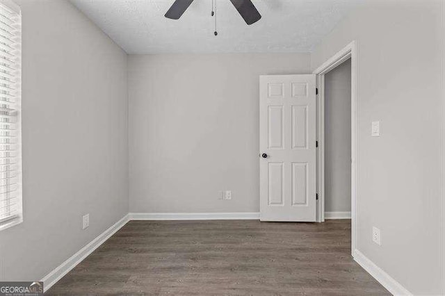 empty room featuring a textured ceiling, ceiling fan, and dark wood-type flooring