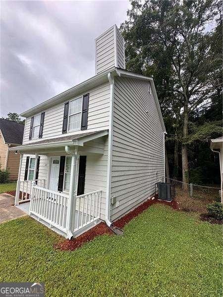 view of side of property with central air condition unit, a lawn, and covered porch