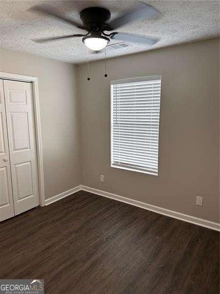 spare room with dark hardwood / wood-style floors, ceiling fan, and a textured ceiling