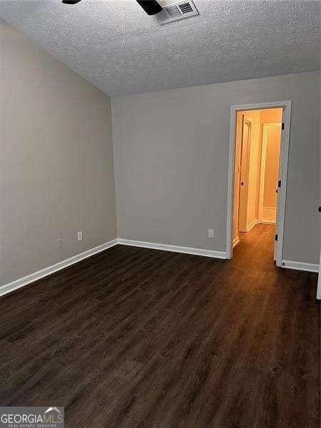 spare room featuring dark hardwood / wood-style flooring and a textured ceiling