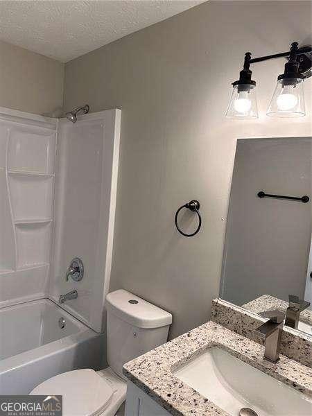 full bathroom with vanity, toilet, a textured ceiling, and shower / washtub combination