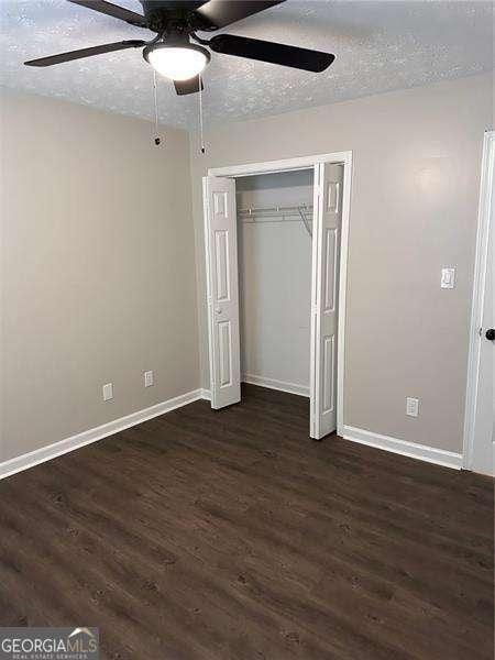 unfurnished bedroom featuring dark hardwood / wood-style flooring, a textured ceiling, a closet, and ceiling fan