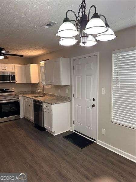 kitchen featuring white cabinetry, sink, stainless steel appliances, and a textured ceiling