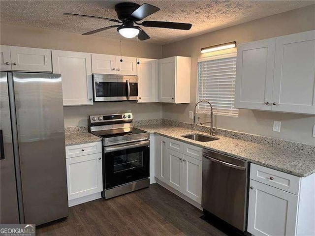 kitchen featuring sink, light stone countertops, appliances with stainless steel finishes, dark hardwood / wood-style flooring, and white cabinetry