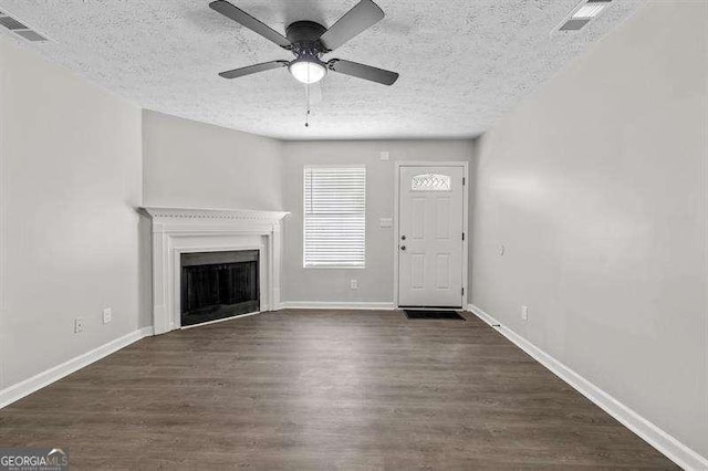 unfurnished living room with ceiling fan, dark hardwood / wood-style flooring, and a textured ceiling