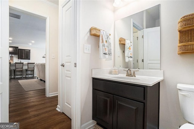 bathroom with toilet, hardwood / wood-style floors, vanity, and ornamental molding